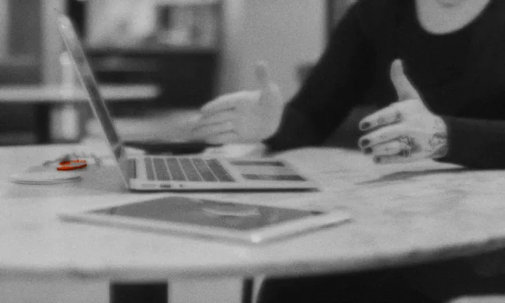 Manos que explican algo sobre una mesa con una laptop y una tablet